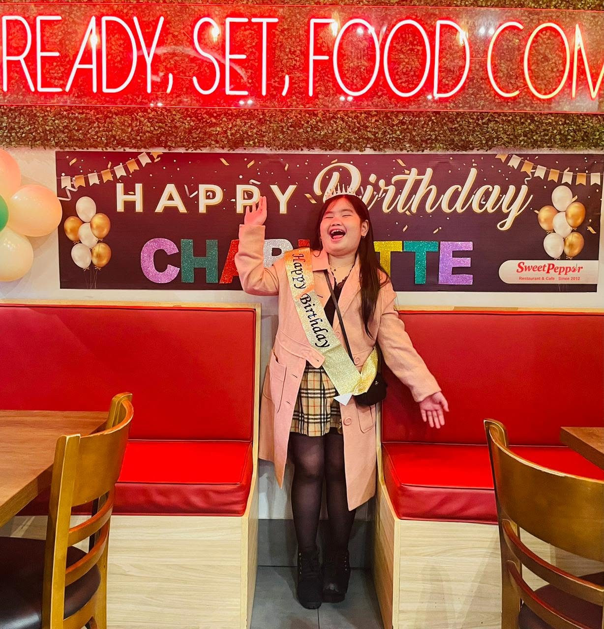 Guest posing in front of a Happy Birthday banner in the red booth area
