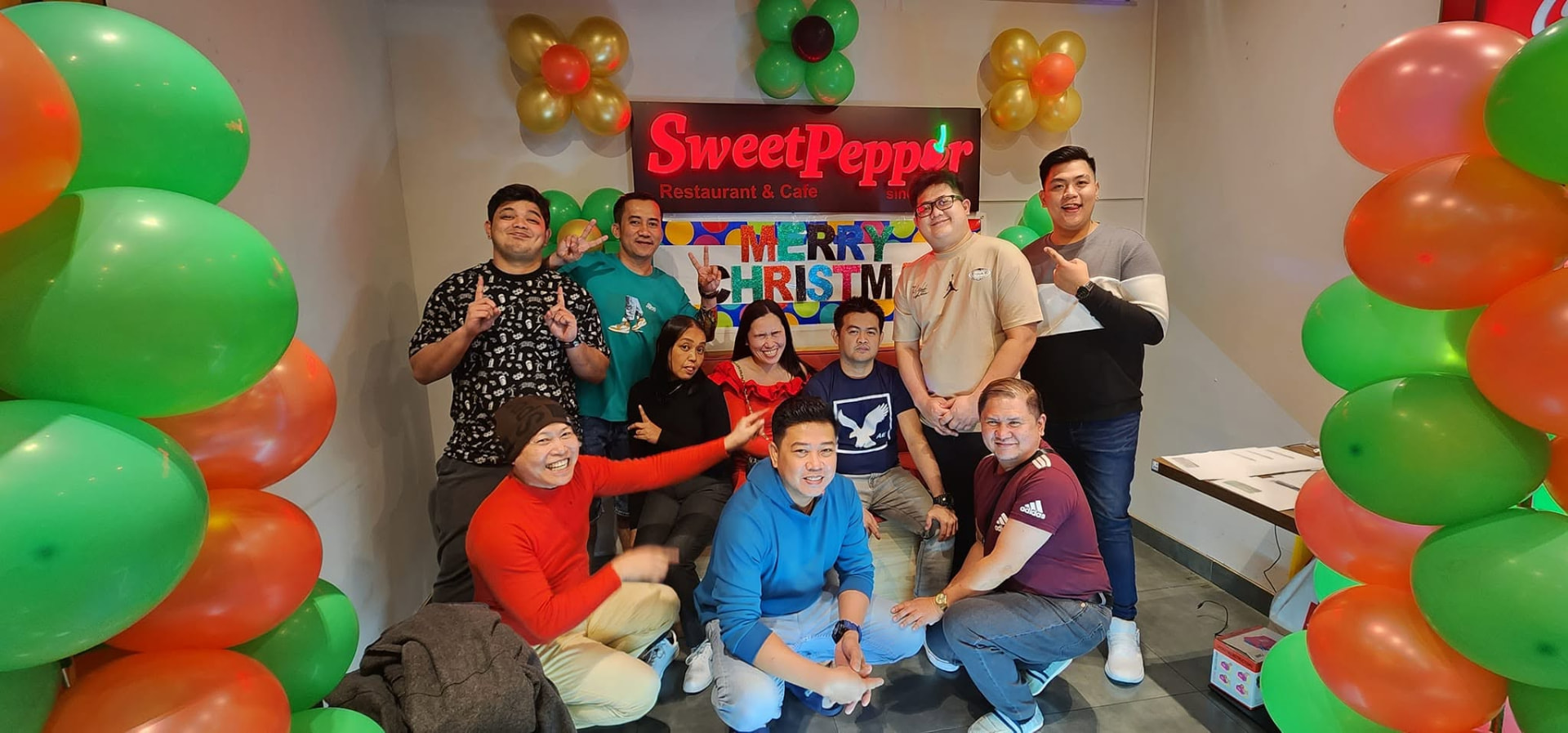 Christmas party guests under the Sweet Pepper Restaurant & Cafe sign